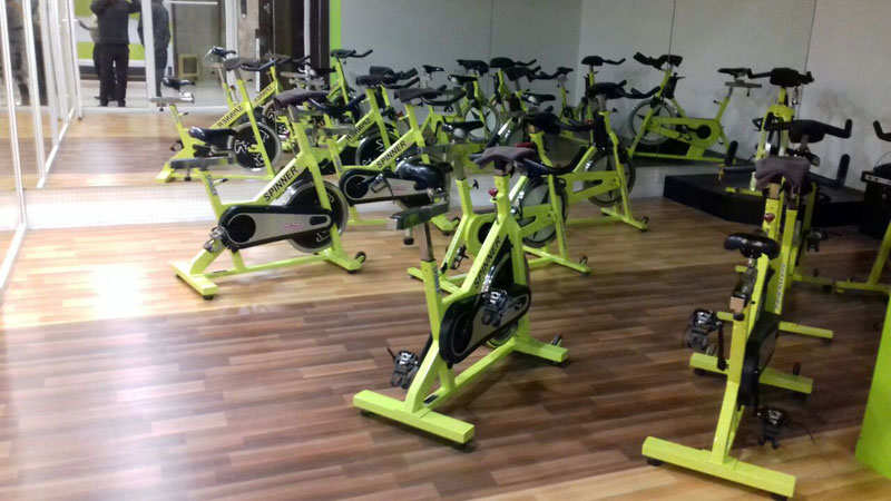 Spinning studio with rubber flooring and yellow exercise bikes