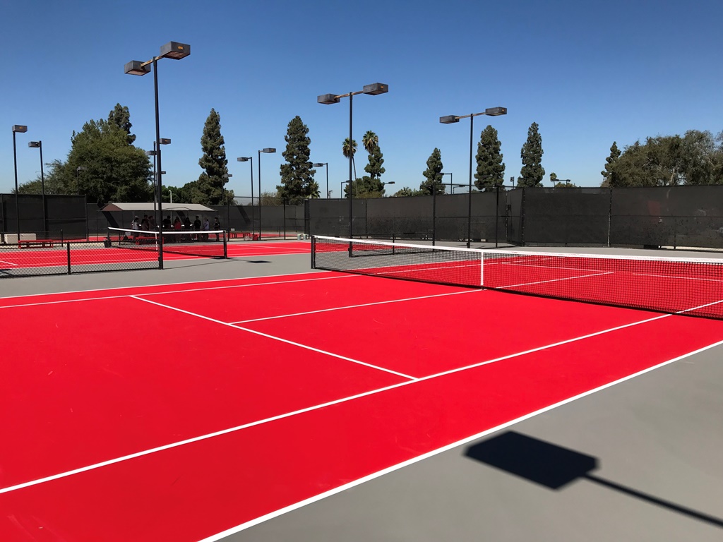 Multiple red outdoor tennis courts with professional facilities