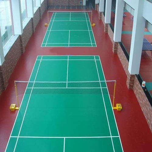 Indoor badminton courts with green playing surface and red surrounding areas